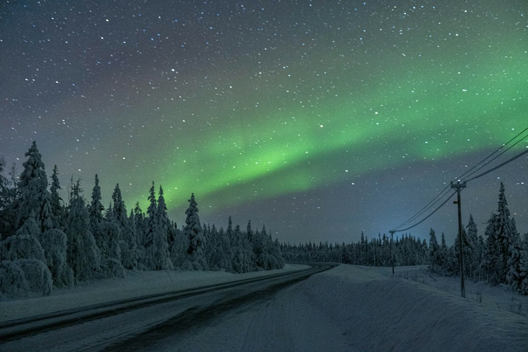 Aurore boréale verte au-dessus d'une route en Laponie finlandaise