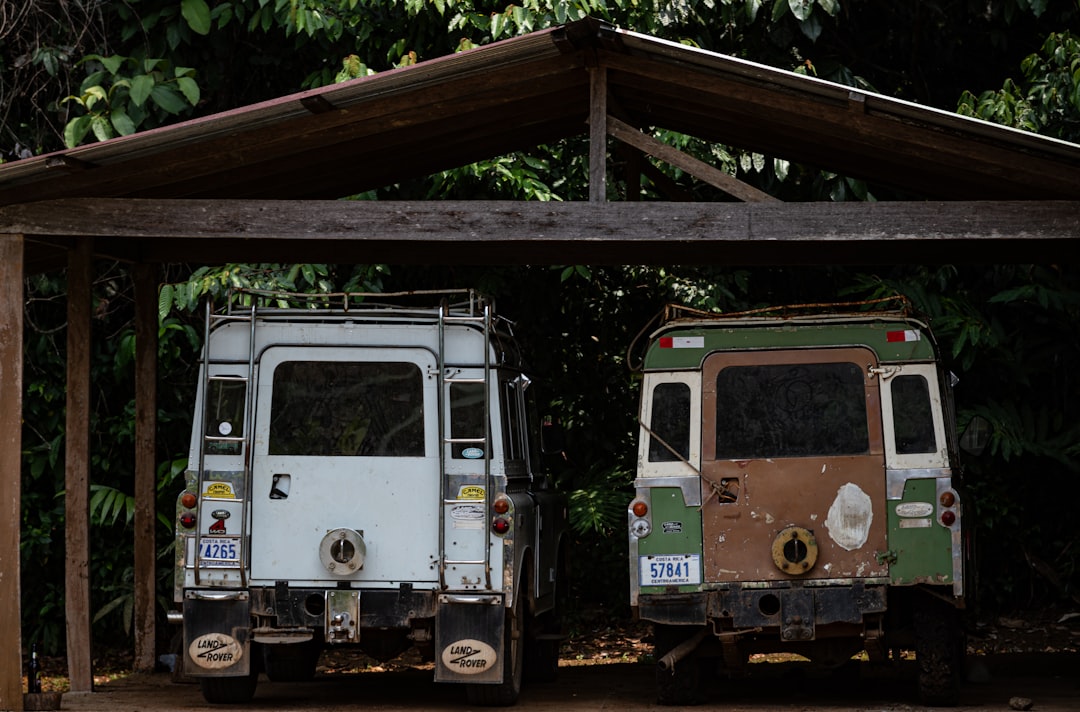 Deux véhicules 4x4 tout-terrain garés sous un abri en bois dans la jungle, immatriculés au Costa Rica