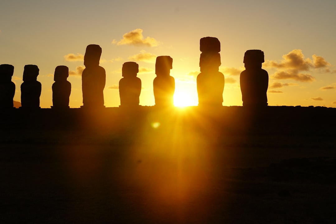 Moai statues silhouetted against a vibrant sunset on easter island