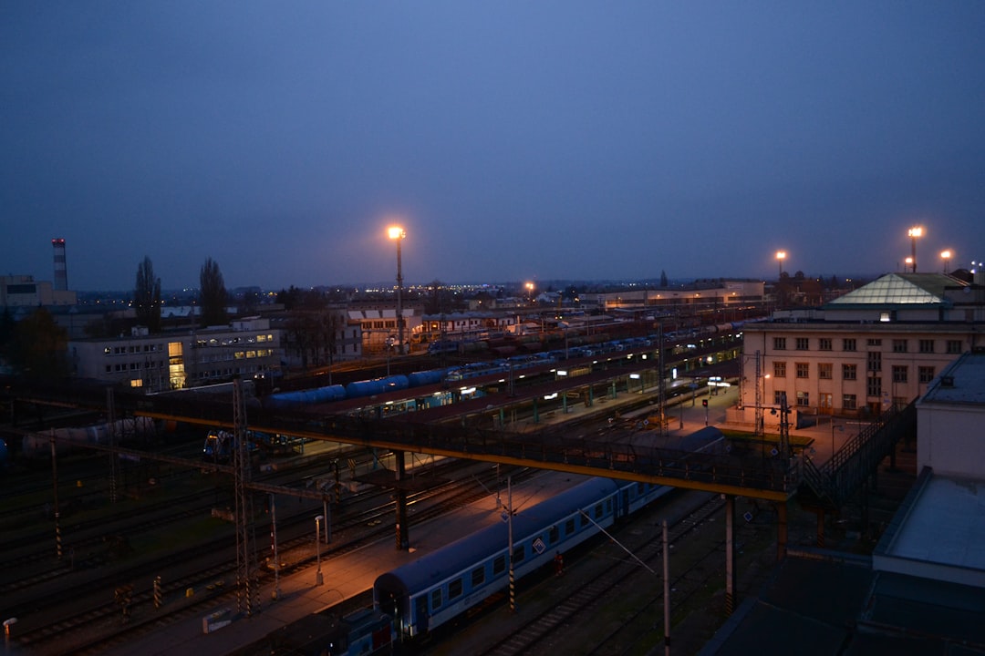 Gare ferroviaire européenne au crépuscule, quais et voies éclairés à la tombée de la nuit