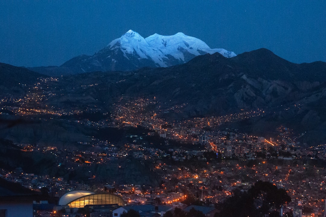 La Paz, Bolivie : la ville lumineuse en contrebas avec le mont Illimani enneigé en arrière-plan au crépuscule