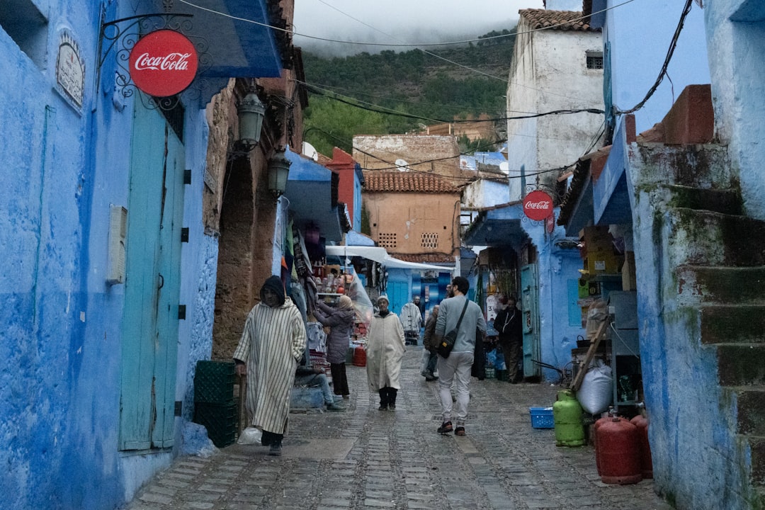 Ruelle étroite d'une médina marocaine avec des passants, murs en bleu et blanc