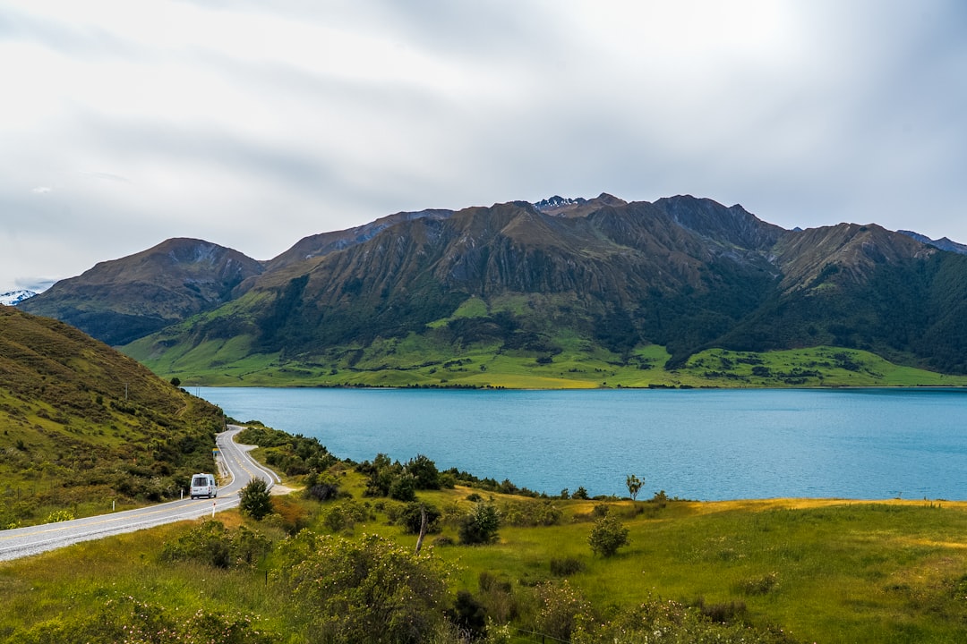 Route sinueuse longeant un lac de montagne en Nouvelle-Zélande, typique d'un road trip en solo