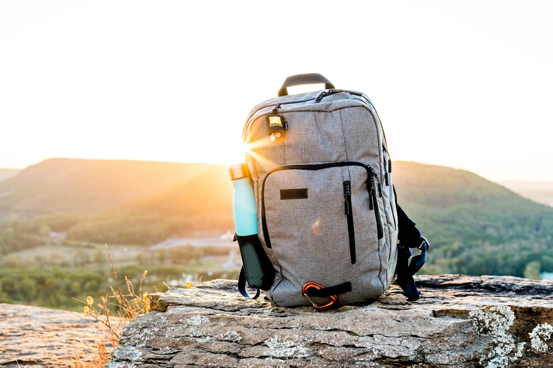 Sac à dos de randonnée gris et noir posé sur un rocher au coucher du soleil, idéal pour les voyages en cabine