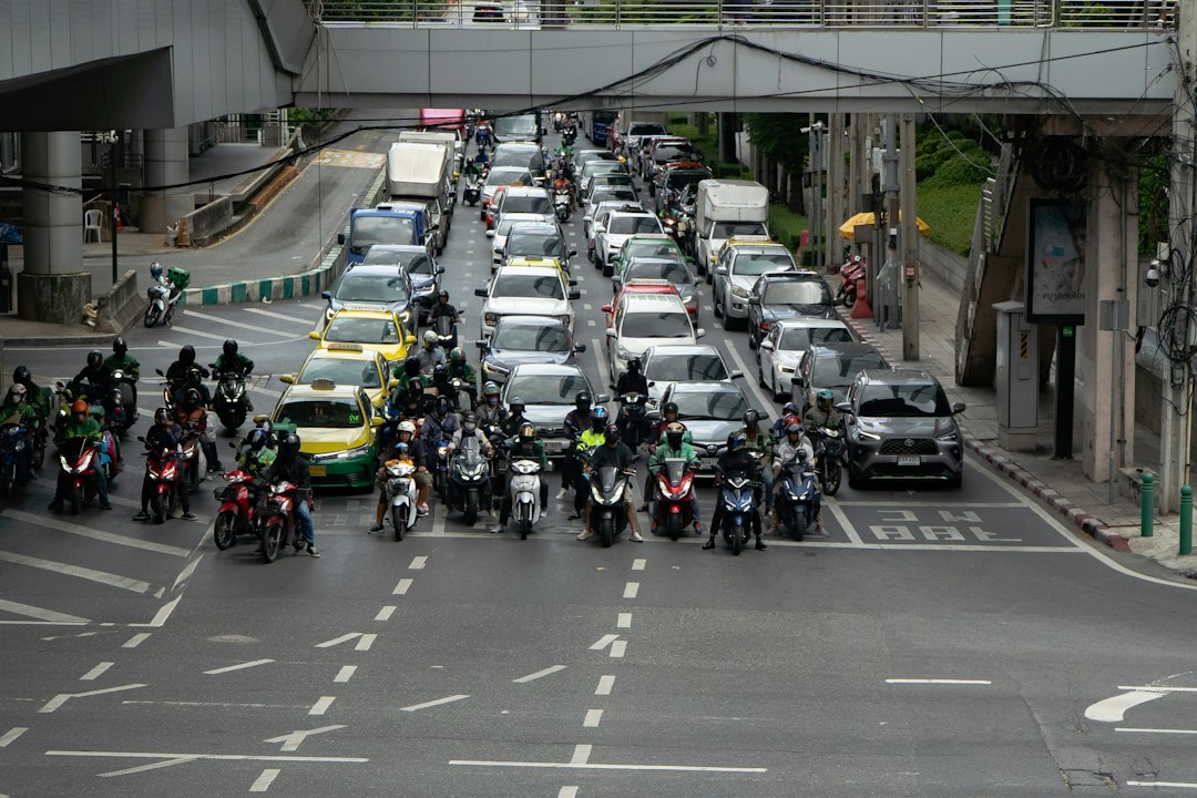 Motos et voitures arrêtées à un carrefour urbain en Thaïlande
