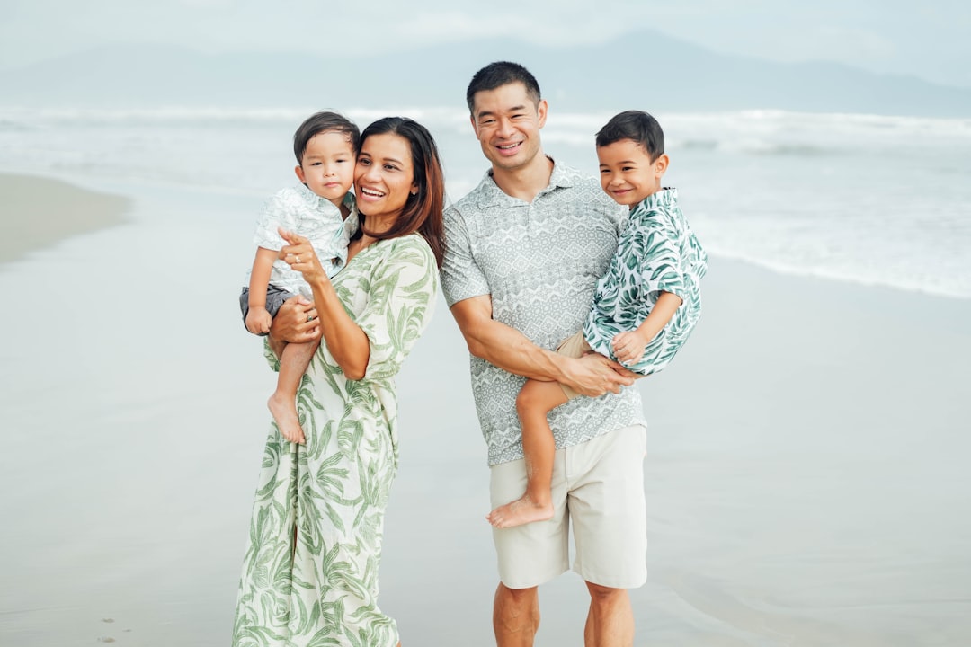 Family posing on a beach with the ocean behind them