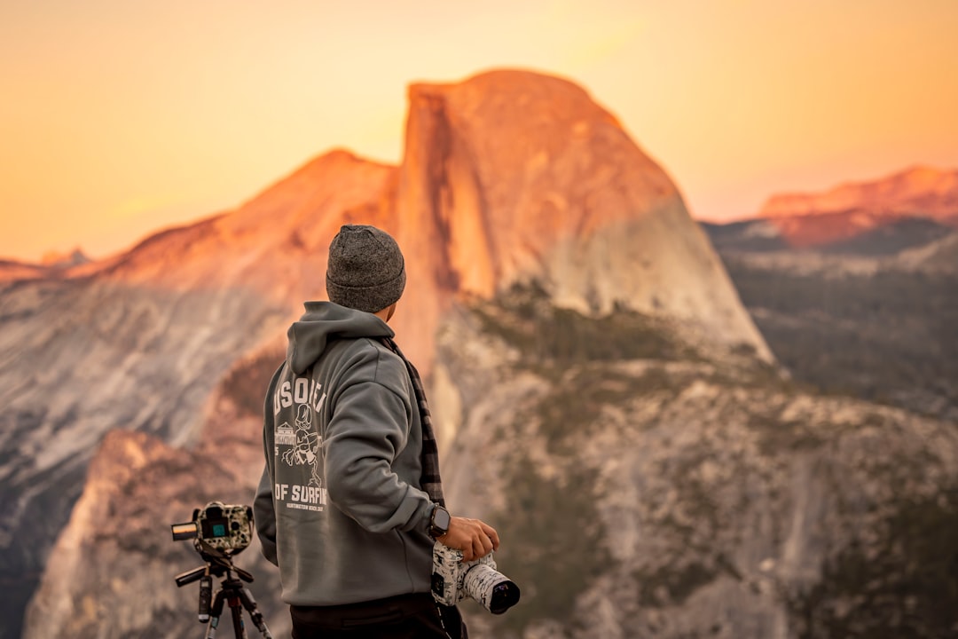 Man with camera watches sunset over half dome.