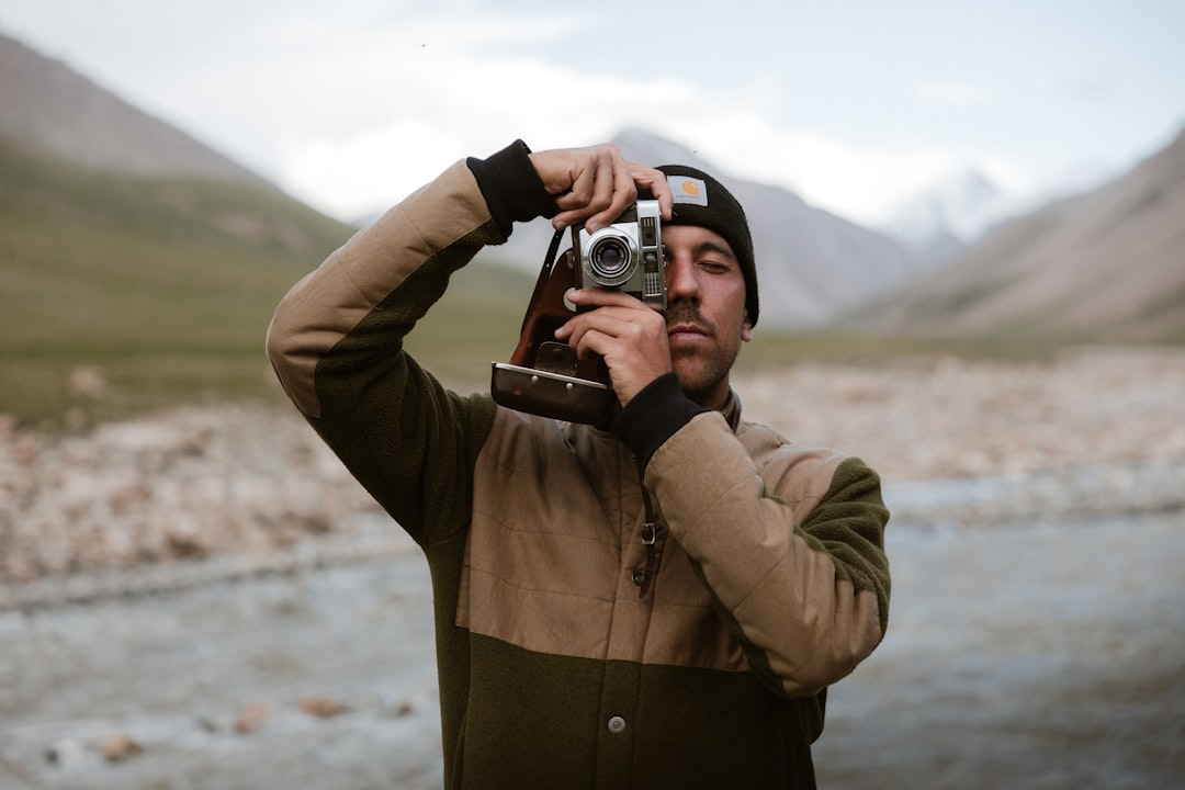 Man holding vintage camera in mountainous landscape