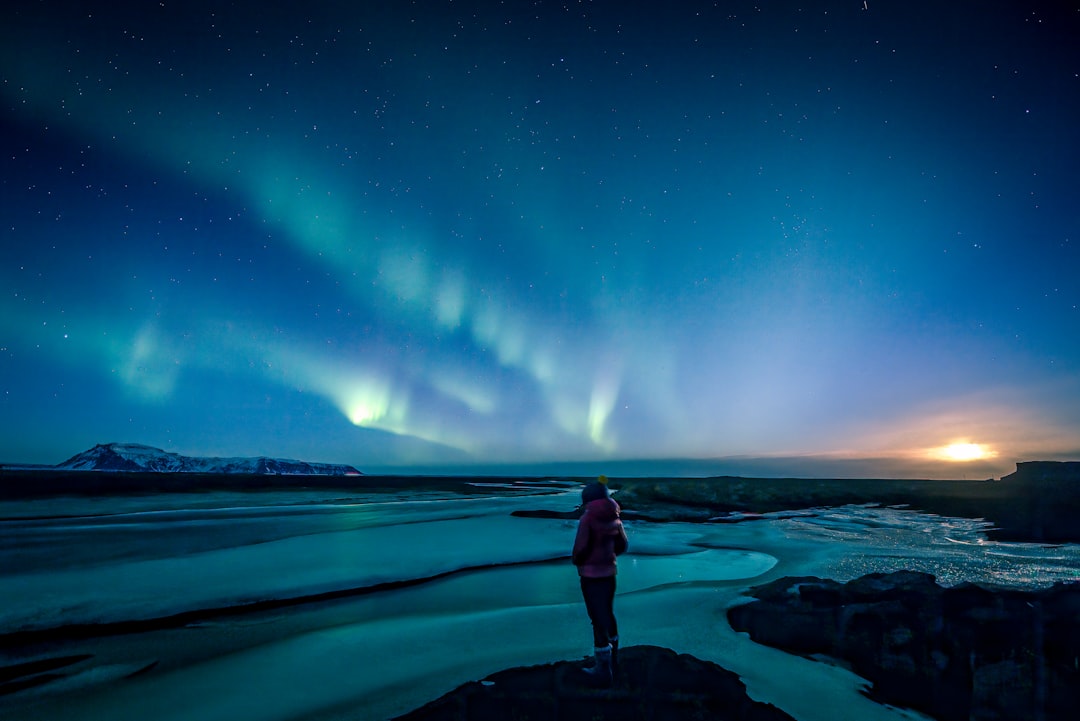 Voyageur seul debout sur une formation rocheuse en Islande sous un ciel bleu