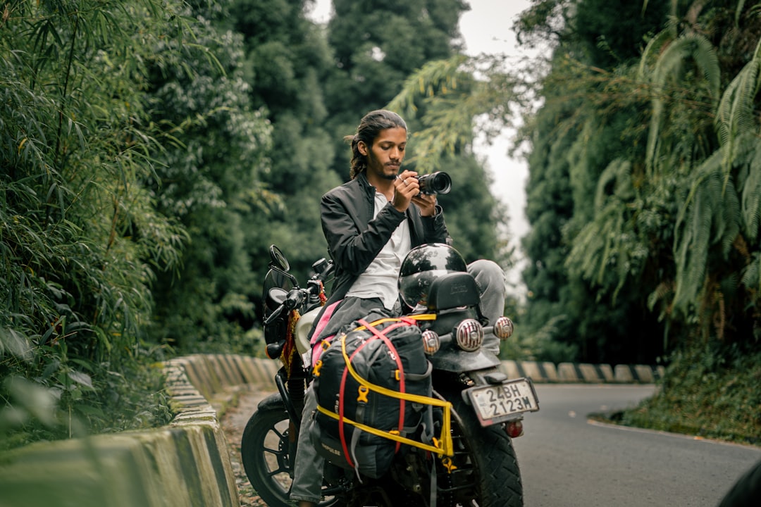 Man with camera on motorcycle in lush forest