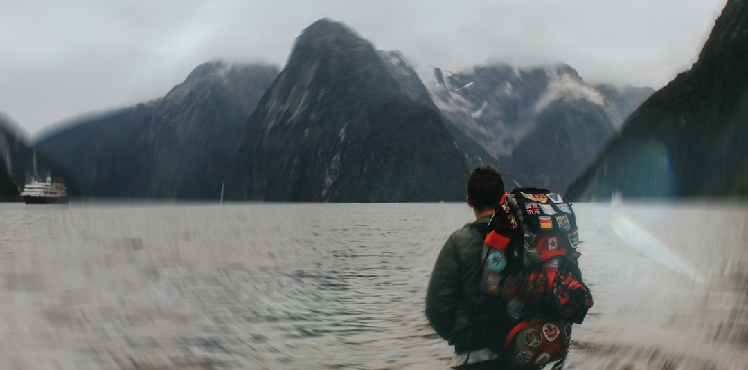 Hiker views mountains with a boat in the distance.